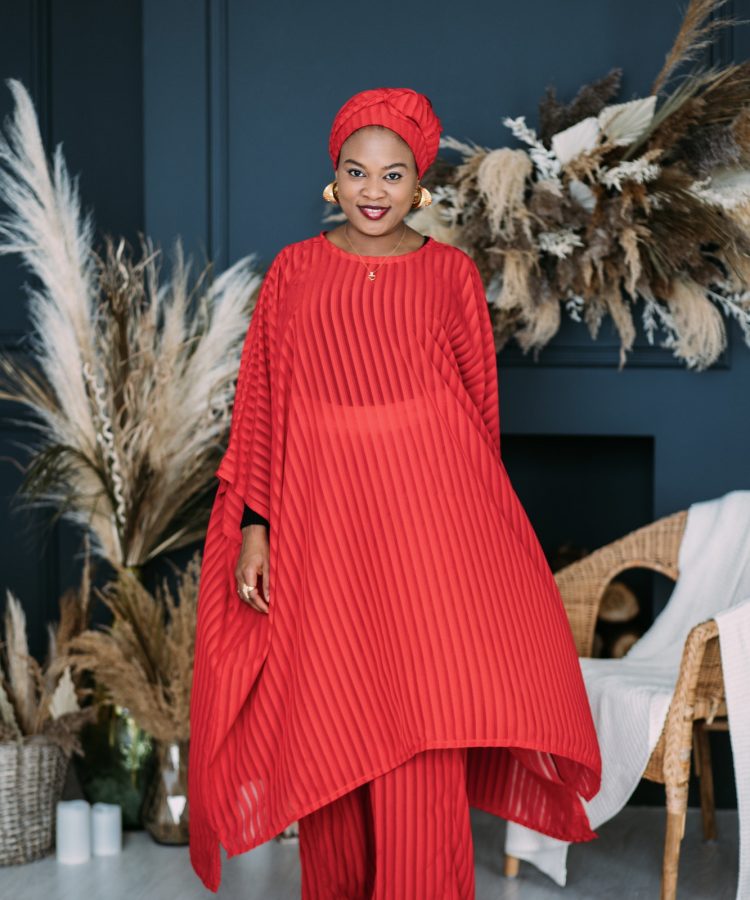 Young african american woman wearing african style red bright suit and head shawl, smiling confident